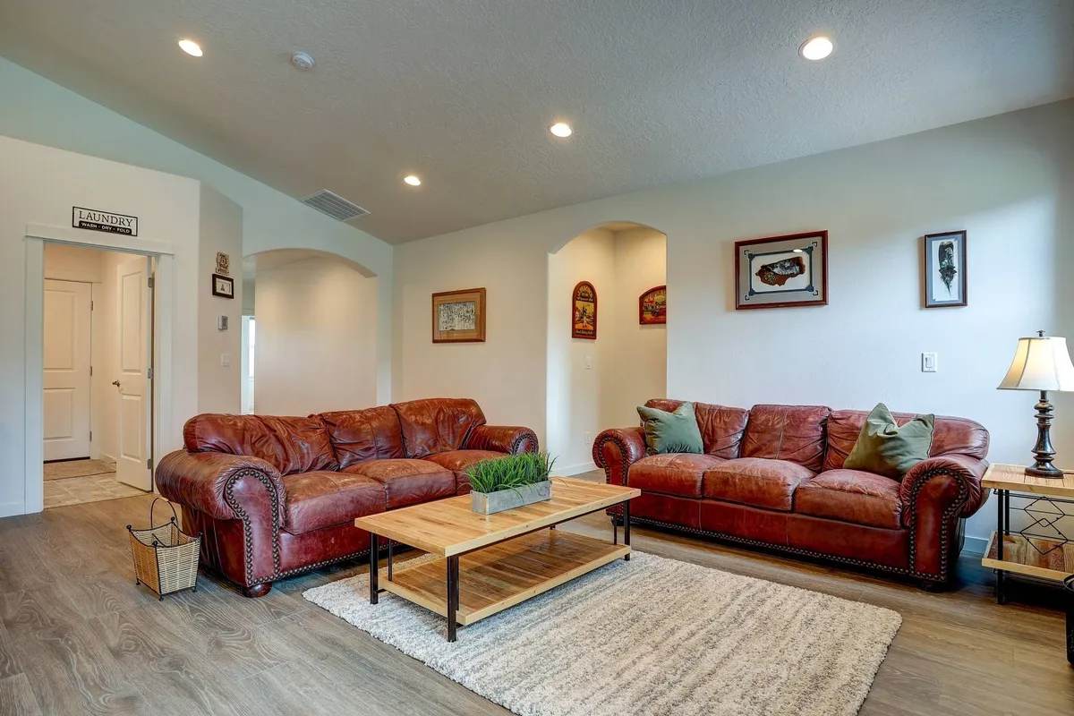 An inviting living area featuring two plush leather sofas, a wooden coffee table, and tasteful wall art. The space is well-lit and arranged for comfort, making it ideal for relaxing or socializing with friends and family after a busy day.
