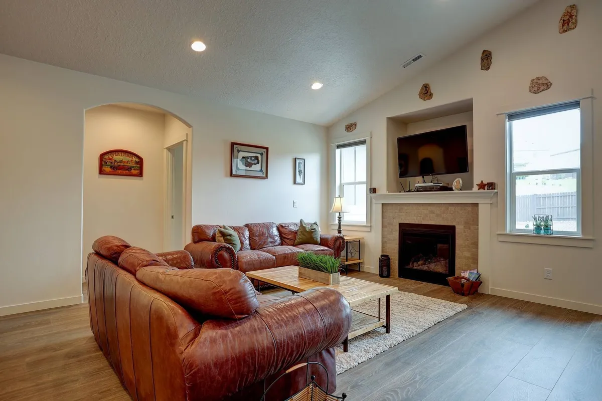 A warm and inviting living area features a leather sectional sofa arranged around a glowing gas fireplace. The coffee table and surrounding decor foster a cozy environment for conversation, relaxation, and evening gatherings after a day's adventure.