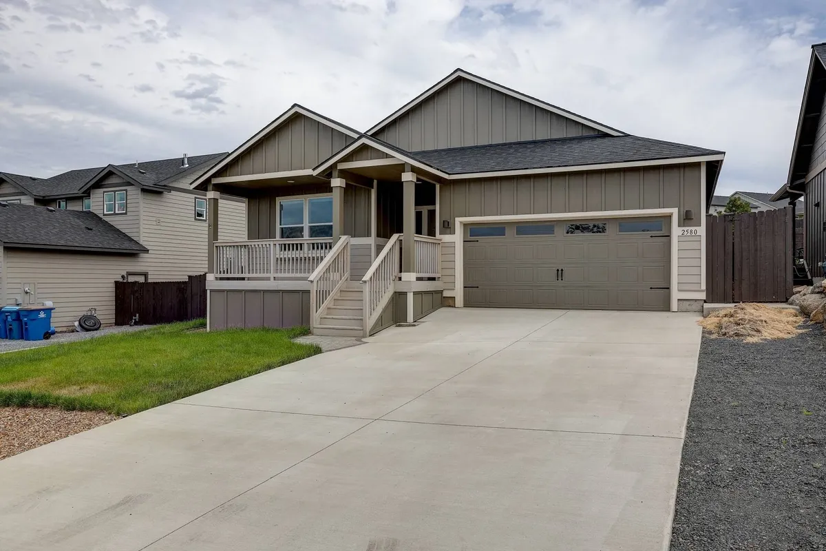 An inviting view of the home's front porch, garage, and landscaped lawn, suggesting a welcoming and peaceful residential atmosphere. The soft outdoor lighting hints at the comfort of evenings spent outside, perfect for relaxing or socializing.